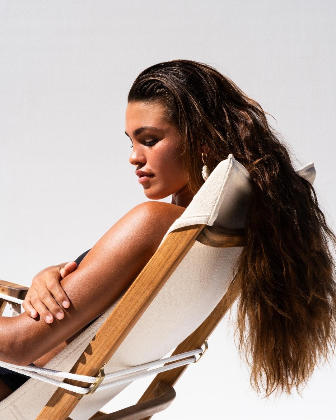 Woman with long hair sitting in a Shorebird Chair against a plain background