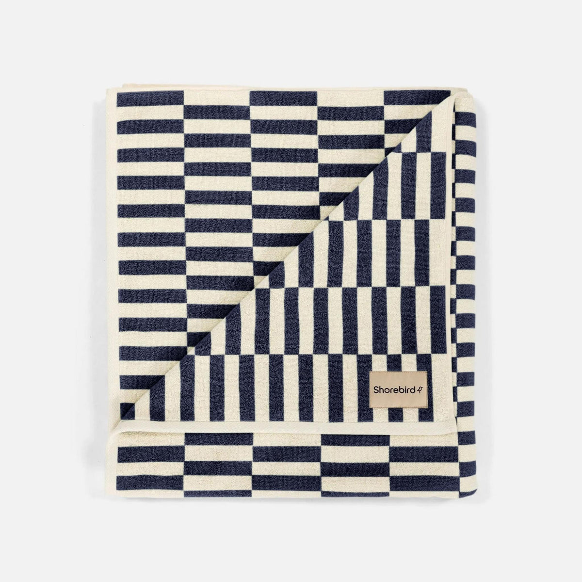 The Oversized Beach Towel in navy and cream jacquard terry check, folded with Shorebird label #color_nantucket