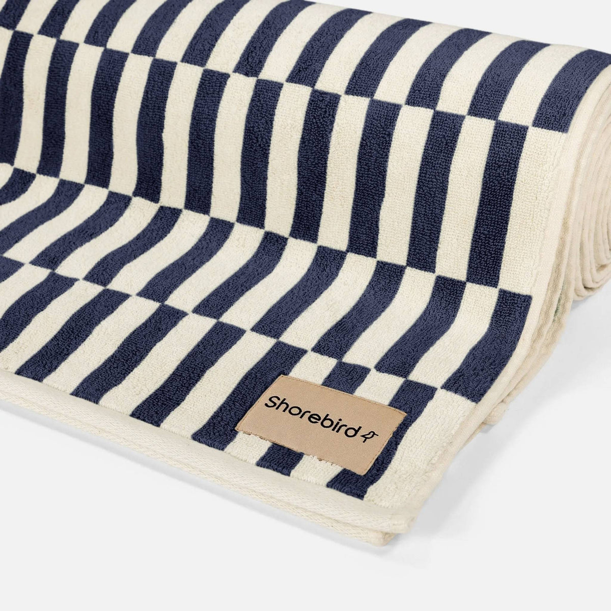 Close-up of plush terry loops and the Shorebird woven label on the navy check beach towel #color_nantucket