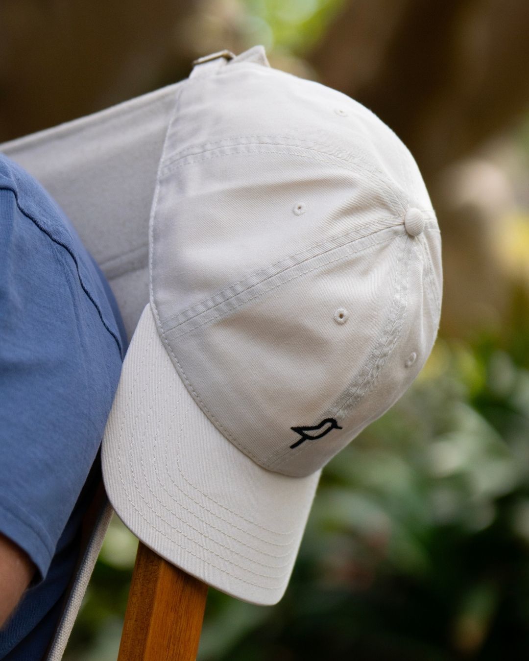Shorebird Dad Hat Natural resting on back of Shorebird Chair