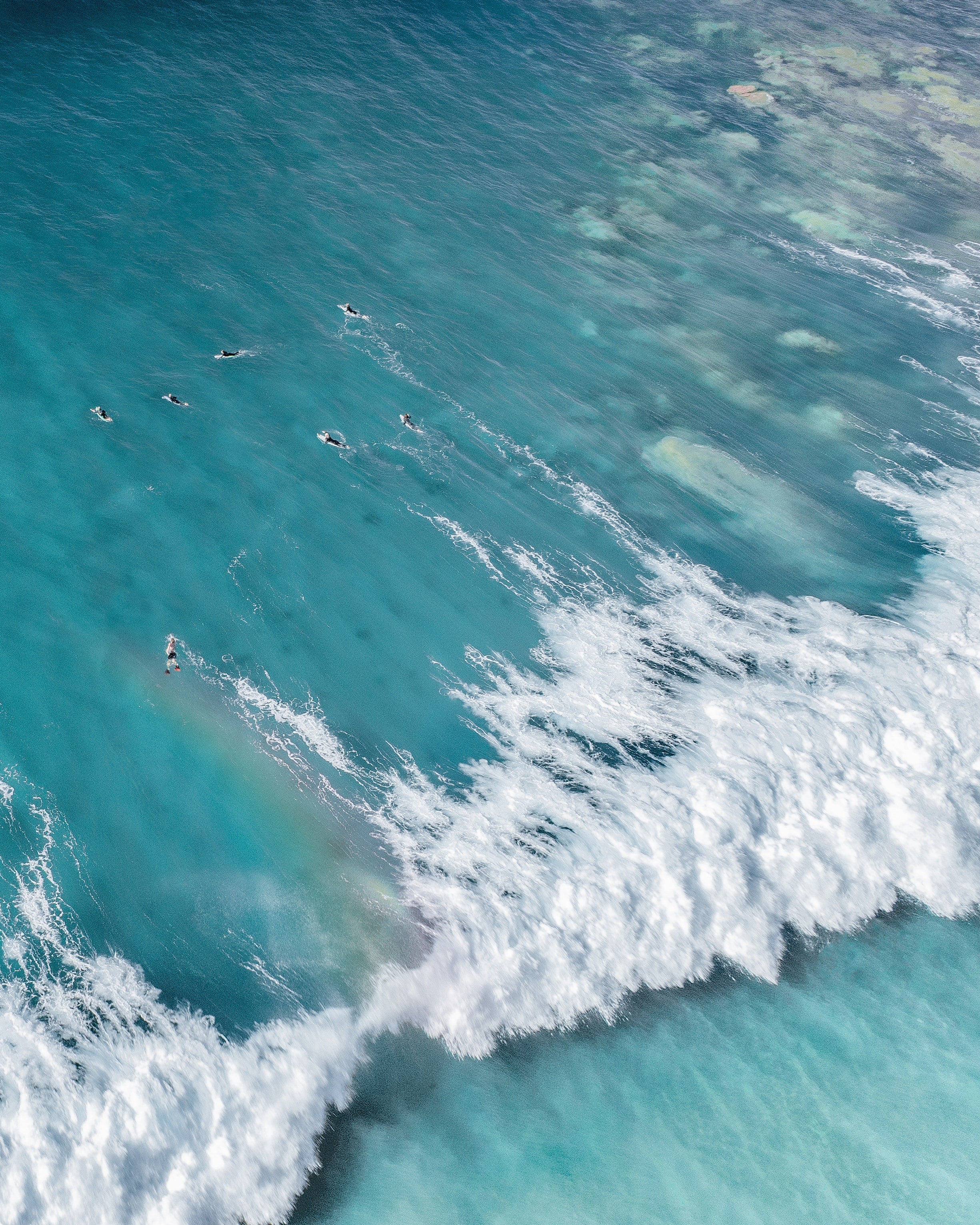 Aerial view of the ocean with wave crashing and surfers in the water